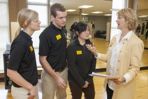 Students Chelsea Boesel (left), Adam Irwin and Francesca Paras talk with UWM’s Carlynn Alt. Carlynn Alt, a clinical associate professor in the Department of Kinesiology in the College of Health Sciences, is a cancer survivor. She teaches students who work with cancer patients twice a week at Elite Sports Club in Glendale. Alt has found ways to use her own experience to inform her teaching and patient care. The work she and her students do is one of many examples of UWM’s community engagement.