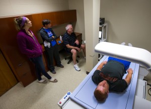 (from left to right): Abigail Fischer (biology major), Ryanne Breckenridge (certified athletic trainer), and Scott Soja (assistant professor in the department of health and human performance) performs a DXA scan on a UW-Platteville football player. 