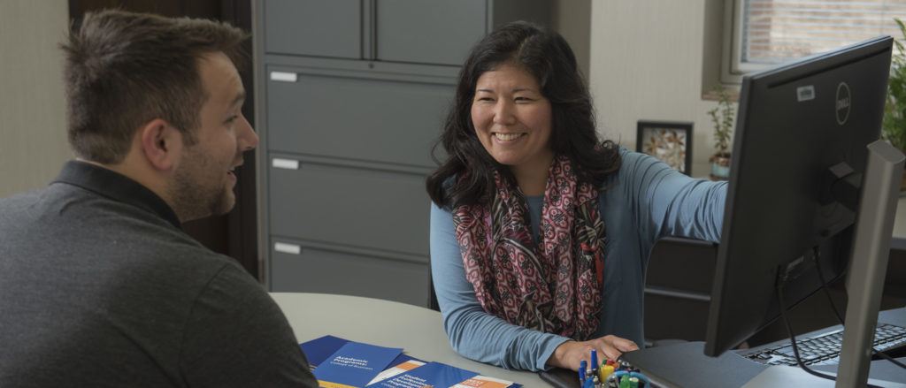 A UW-Eau Claire advisor is talking with a student and sharing information on her computer screen.