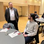 Michael Lango, standing, and Nathan Callope, seated, both of UW-Whitewater, have a conversation during a break at the UW System Navigate and Advising Workshop at UW-Stevens Point in March 2023.