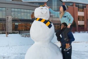 Photo of UWEC students building a snowman