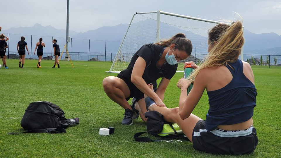 Photo of National Women’s Soccer League (NWSL) athletic trainer and University of Wisconsin Oshkosh alumna Lindsey Toman ’06 (center)