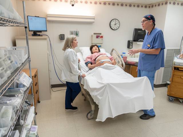 Photo of nursing faculty setting up Lucina, the new obstetrics manikin.