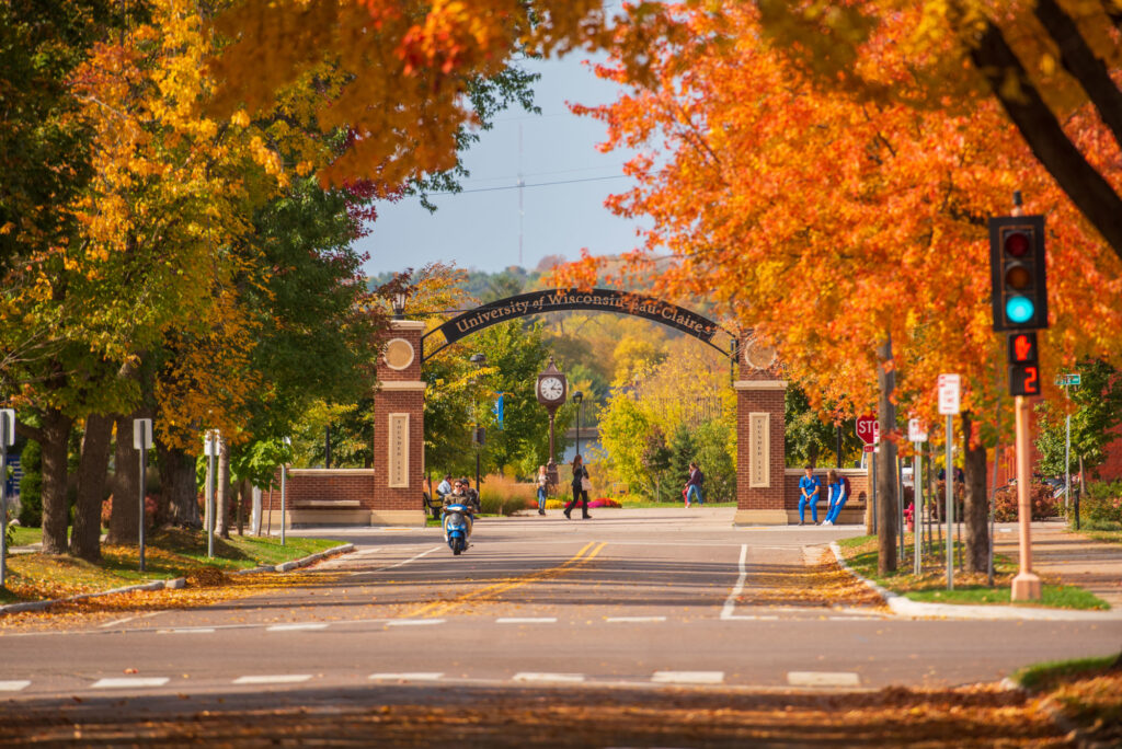 Photo of UW-Eau Claire campus entrance. Students make their way through lower campus on a warm fall day. The Stowe Gateway is visible in the scene. UW-Eau Claire is partnering with The College of New Jersey to examine ways for higher education institutions around the country to develop more innovative collaborations with industries.