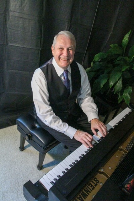 Photo of UW-Parkside alumnus and musician George F. Baumgardt seated at a piano
