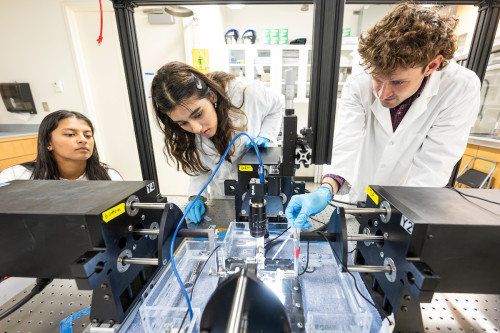 Photo: Daniel Pearce (right), graduate student in biomedical engineering, works with students on a testing sample in a lab in the Engineering Centers Building. Photo: Bryce Richter