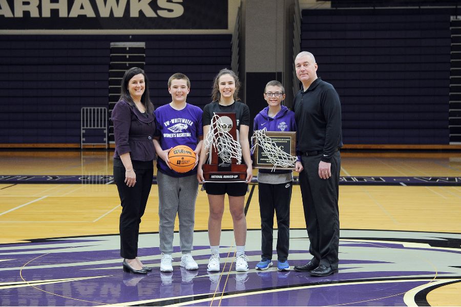Photo of the Carollo family, including, left to right, Keri, Matthew, Kacie, Tyler, and Joe, holding the team’s conference championship and national runner-up trophies after the Warhawk women’s basketball team’s run to the Final Four in 2022. (UW-Whitewater athletics photo/Michael McLoone)