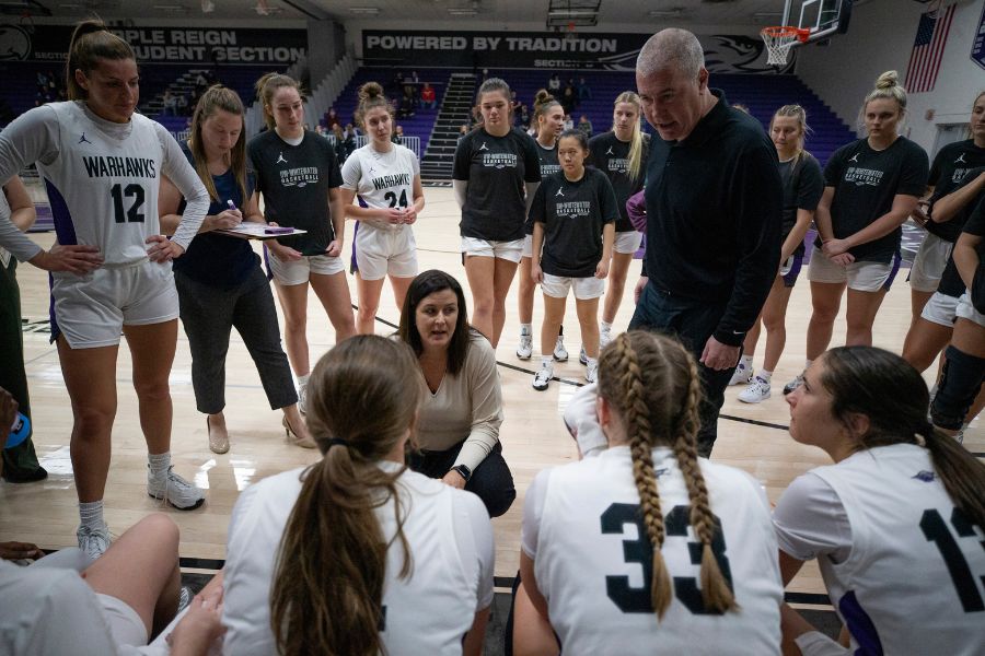 Photo of head women's basketball coach Keri Carollo, center, and her husband Joe, an assistant, talking to players. Their daughter Kacie, right, is among the players. The Warhawk women's basketball team defeated UW-Stevens Point, 53-44, on Jan. 10, 2024, in Kachel Gym. With the win, the Warhawks matched their best start in program history with 14 wins and no losses. (UW-Whitewater photo/Craig Schreiner)