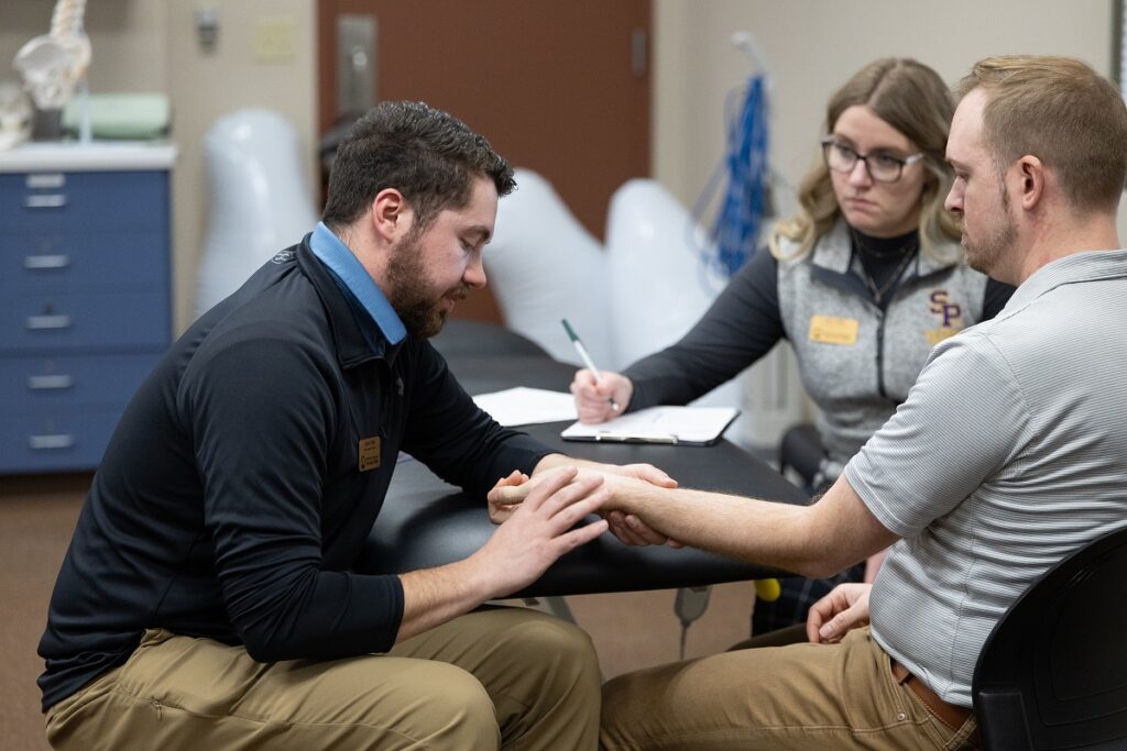 Photo of UW-Stevens Point Doctor of Physical Therapy (DPT) students Caden Prahl and Amy Griffin working with a patient at the UWSP Physical Therapy Clinic housed at the Stevens Point Area YMCA as part of their integrated clinical practice course.