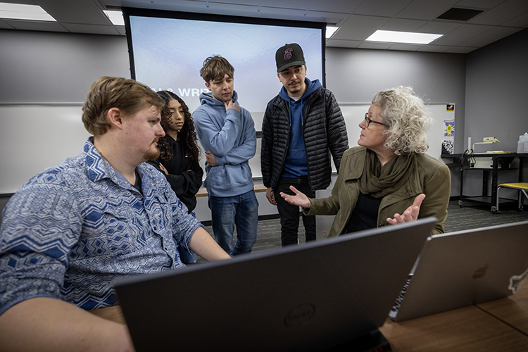 Photo of AI classroom - Doctoral student David Kocik (left) and Shevaun Watson (right), associate professor of English, talk with students Genoveva Jeronimo Orozco, Drake Olson and Jesus Aguilera. Watson and Kocik created an artificial intelligence literacy program that teaches UWM students how AI works and how to use it. (UWM Photo/Troye Fox)