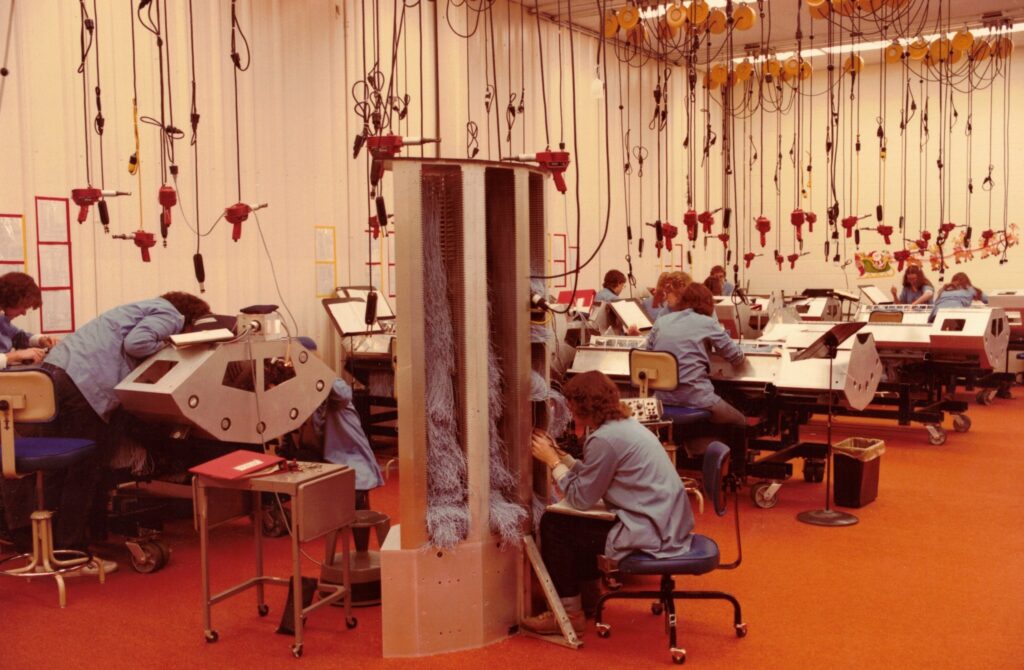 Photo: Dylan Helwig, a senior history major at the University of Wisconsin–Eau Claire, is researching the history of Cray Inc., a company credited with building the first true supercomputer in 1976. In this photo, wiring tools hang from the ceiling to prevent damage, a practice recommended by Cray employee Sonja Gardner and still used today. (Historic photo provided by the Chippewa Falls Museum of Industry and Technology)