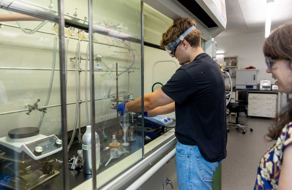 Photo: Roman Domashevsky, a junior majoring in biology with a biomedical concentration, was part of the Dean’s Distinguished Fellowship program this summer. He is pictured working with organic solvents under the fume hood in the Prairie Springs Science Center’s chemistry lab, alongside his faculty mentor, Robin Grote.