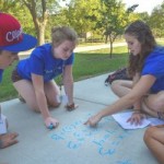 students writing messages on a sidewalk with chalk