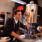 Physics majors Marion Titze and Spencer Twining and Assistant Professor Ozgur Yavuzcetin peer at an evaporator in a physics lab in Upham Hall, on January 22, 2016. The equipment is used to make sensor patterns on silicon wafers, a process called shadow mask evaporation. Photo by Craig Schreiner. - See more at: http://www.uww.edu/news/archive/2016-04-ibuttonlink#sthash.uwpYYmBv.dpuf