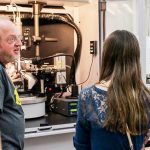 Darya Pronina of Waunakee Middle School and a friend look on as Dan Frankel, from the scientific instrument maker Bruker Corp., demonstrates a single-crystal X-ray diffractometer in the UW–Madison Chemistry Department. (Photo by Libby Dowdall)