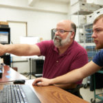 UWL associate professor of archaeology and a student working together at a computer
