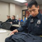 Photo of Mark Vang, an officer with the Eau Claire Police Department, who is looking at a vest he will wear as part of a research project with UW-Eau Claire kinesiology students and faculty to determine if the vests will help ease back pain among police officers.