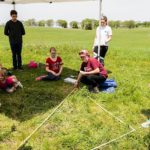 Photo of recent UW-Madison alumna Sarah Taylor, squatting at center, and Aleesha Kozar, standing at center, demonstrating a method for accurately measuring square grids of land as groups of sixth graders visiting from Fort Atkinson Middle School tour one of four educational stations temporarily set up at Aztalan State Park, a prehistoric Native American site located near Lake Mills, Wis., during spring on May 24, 2018. Funded by a Baldwin Wisconsin Idea Project Grant, the public outreach program is led by UW-Madison Anthropology Professor Sissel Schroeder, who has previously conducted several undergraduate archeological fields schools and research projects at the site. (Photo by Jeff Miller / UW-Madison)
