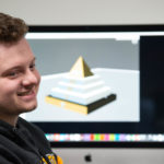 Photo of an art student in a digital fabrication class, who recently gained real-world professional experience working with one of the community's most prestigious employers, Oshkosh Defense.