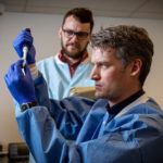 Photo of Peter Thielen, front, working with Tom Mehoke on immediate sequencing of the SARS-CoV-2 genome, the virus that causes COVID-19, at the Johns Hopkins Hospital molecular diagnostics laboratory. Johns Hopkins APL / Ed Whitman