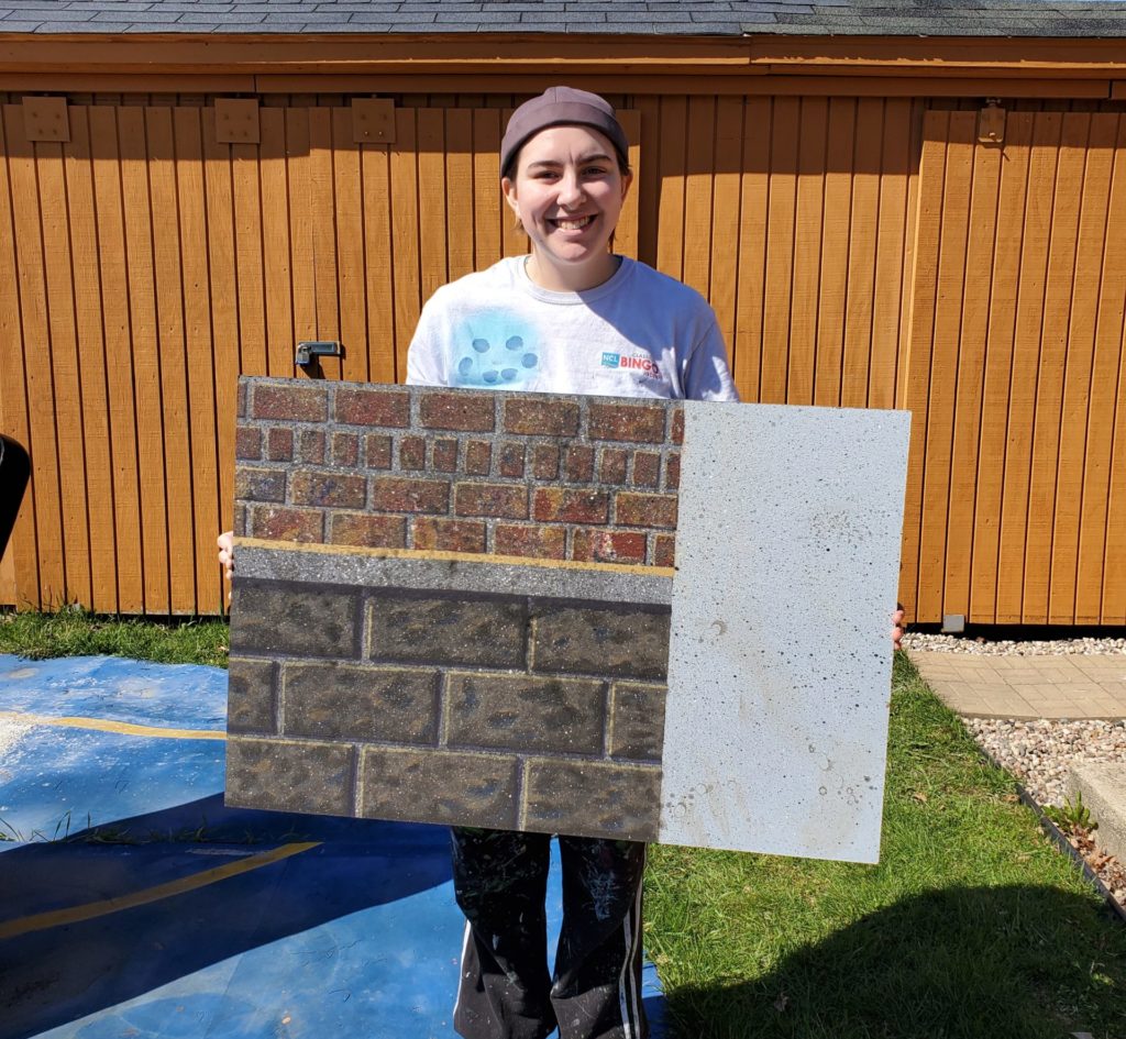 Photo of UW-Parkside student holding an example of a theater scene painting backdrop