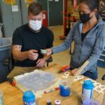 Photo of Zach Heinkel, '18, a composite materials engineer with the Carderock Division of the Naval Surface Warfare Center in Bethesda, Maryland, who is part of a four-person team using 3D printers to produce masks, visors and hands-free door openers for employees at various naval facilities.