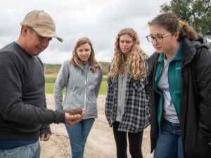 Photo of Farm worker Roberto Montalvo (left) talking with Blugolds Grace Johnson, Amanda Cassin and Bethany Johnson during the students’ visit to a western Wisconsin farm.