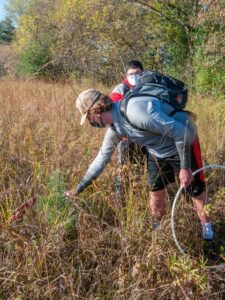 Photo of UW-Stout students Ben Ebben and Cristian Ayalo-Carpintero preparing to identify plants. The plastic ring was used to determine a consistent sample area.