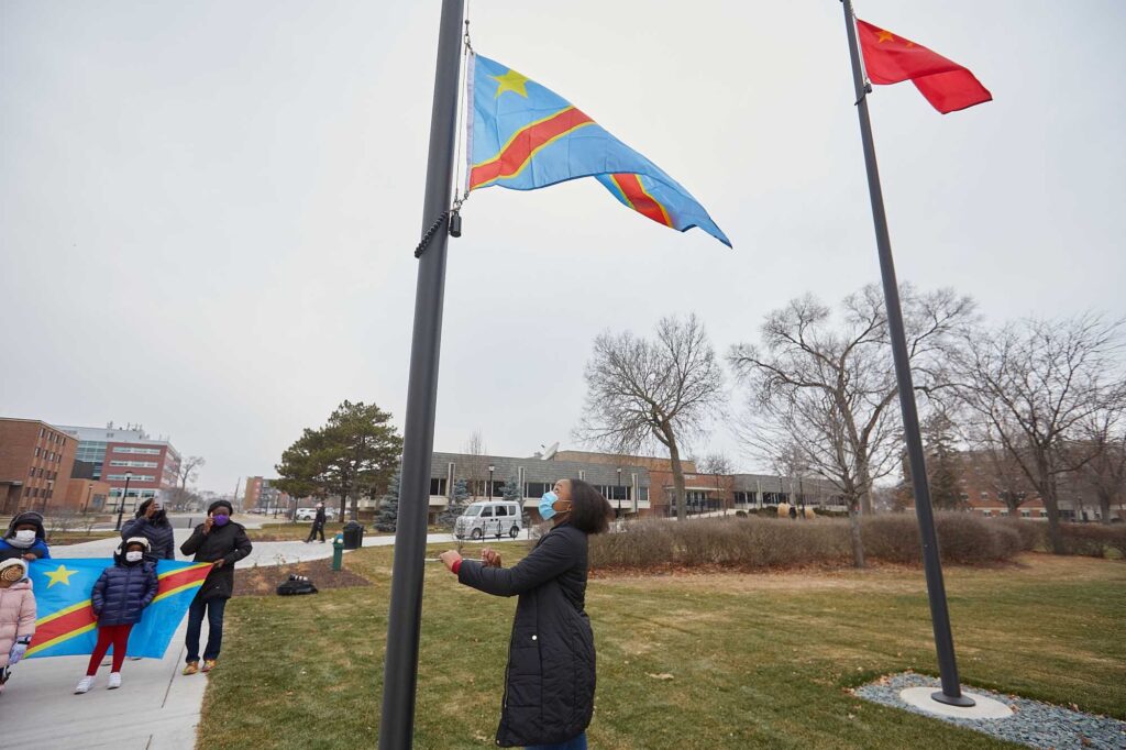 Photo of UWL Senior Vanessa Mbuyi Kaja raising the flag of the Democratic Republic of Congo for the first time on campus during a December 2020 ceremony. “I already knew I was accepted here in La Crosse, but this makes me feel like yes, I can call this my home,” noted the microbiology major.