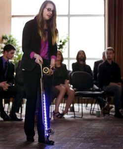 Photo of Kristen Holtan demonstrating a longboard outfitted with LED lights during the CEO elevator pitch competition finals on Wednesday, Oct, 12, 2016, at Whitewater University Innovation Center, in which she won first place.