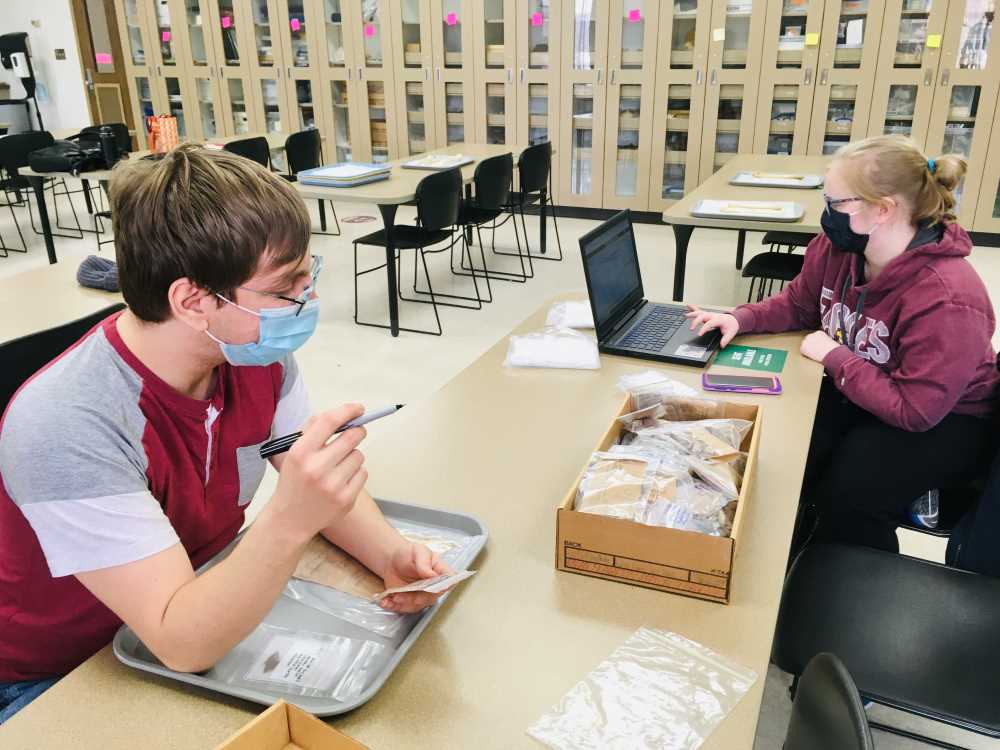 Photo of UWL students Miles Martinez, left, and Lauren Brewer documenting archaeological materials in the UWL Archaeology Lab during the spring 2021 semester.
