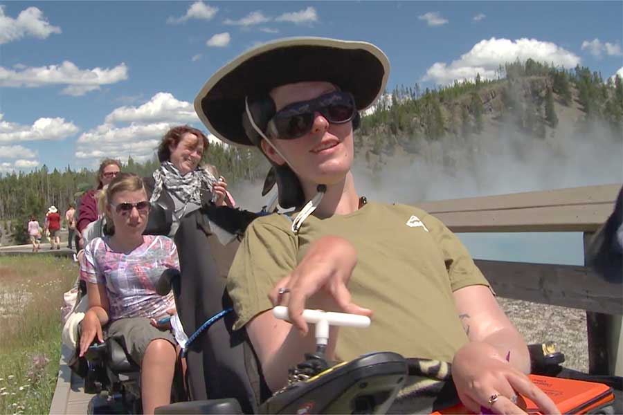 Photo of Brittany Saylor, a biology major, who was one of three UW-Whitewater science students using wheelchairs who traveled to Yellowstone National Park in the summer of 2010 for a two-week field study program led by George Clokey, biology lecturer, seen in the background wearing a red T-shirt. “I wasn’t concerned at all (about the trip),” said Saylor. “I was super excited. Had the countdown going on the laptop… I was super stoked.” Pictured to the left of Saylor was Casey Stark, science and business major.