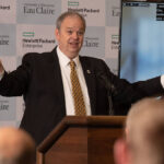 Photo of UW-Eau Claire Chancellor James Schmidt talking about a new public-private collaboration between Hewlett Packard Enterprise and the university at a Monday press conference. Pictured in the video screen is Mayo Clinic Health System Dr. Rajeev Chaudhry.