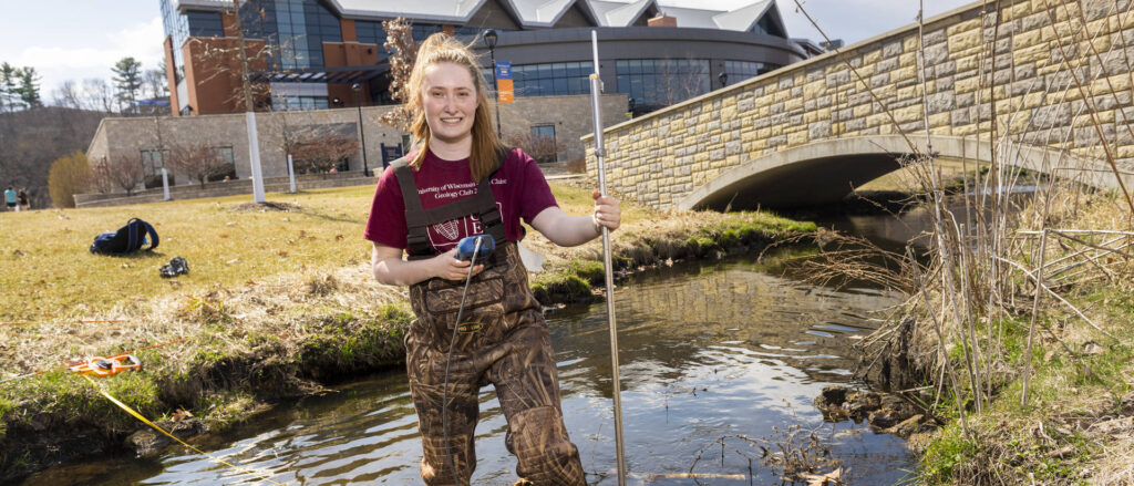 Photo of senior Katherine Langfield collecting research samples in Little Niagara Creek on lower campus. Langfield, who will graduate in May with a degree in geology, says research has been a big part of her undergraduate education at UW-Eau Claire.