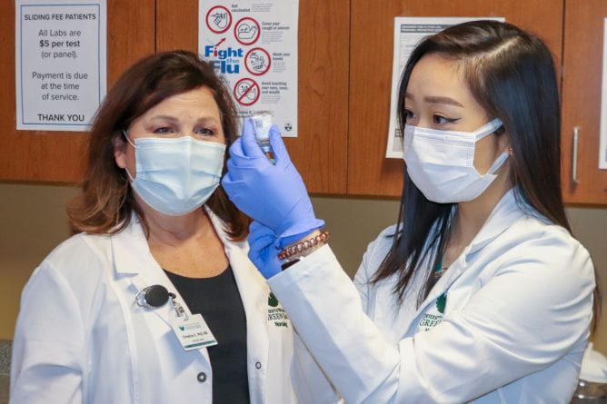 Photo of UW-Green Bay Nursing student, Precious Yang drawing up the Moderna COVID-19 vaccine to immunize a patient at the Lakeshore Community Health Center in Manitowoc on Friday, March 26, 2021. Observing the nursing student, left, Christine Vandenhouten, chair of Nursing & Health Studies at UW-Green Bay.