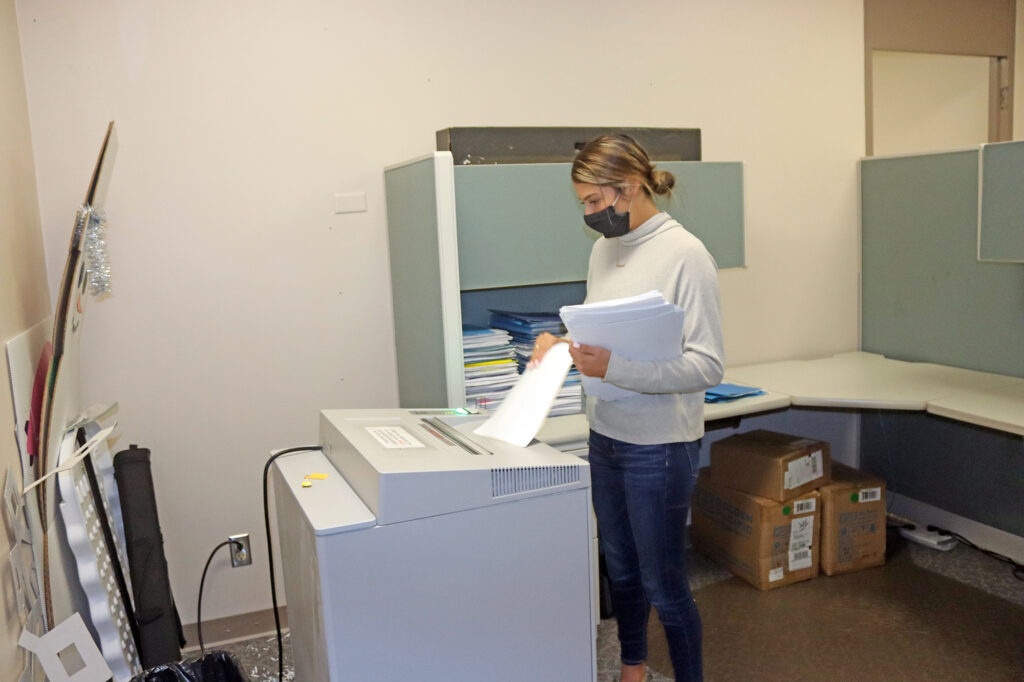 Photo of UW-Stout student Heather Kent, a senior business administration major from Altoona, shredding office paper in the Human Resources office./UW-Stout photo