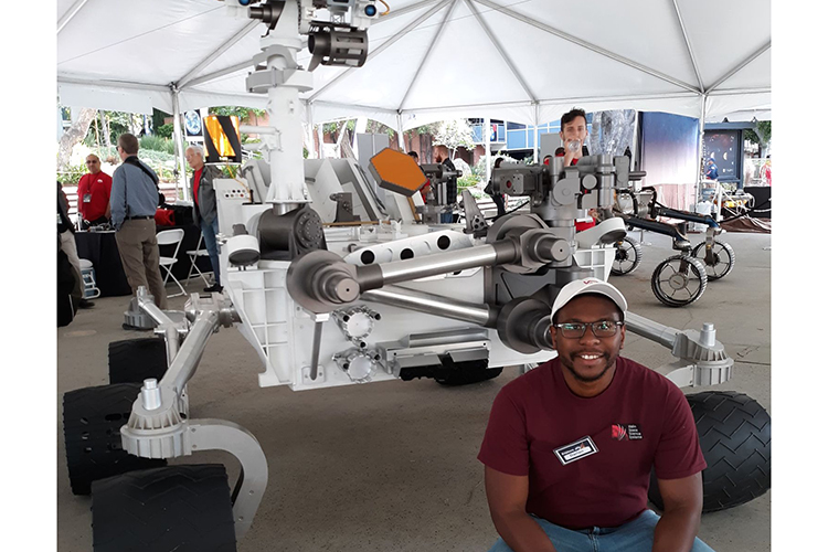 Photo of Darian Dixon posing in front of a model of the Curiosity rover, which landed on Mars in 2012. (Photo courtesy of Darian Dixon)