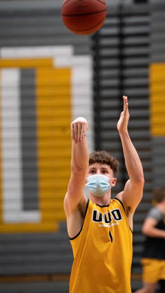 Photo of UW Oshkosh student wearing mask while shooting baskets. UWO officials worked hard to create a culture of mask-wearing during the pandemic.