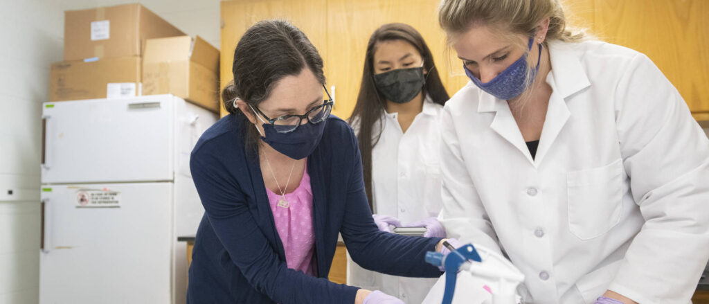 Photo of r. Jamie Lyman Gingerich, a UW-Eau Claire associate professor of biology, who works in a Phillips Hall laboratory with students Kati Sadowska, center, and Caterra Leavens.