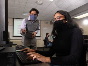 Photo of Dr. Rahul Gomes, assistant professor of computer science, talking with student research Avi Devy Mohan about their work developing an AI framework to detect and monitor filtering devices used by physicians to reduce risks associated with blood clot.