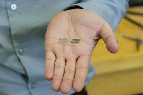 Photo of UW–Madison Professor Xudong Wang holding a fracture electrostimulation device he and his lab designed. When placed over a fracture, the device generates electricity from movement, accelerating bone healing. JASON DALEY