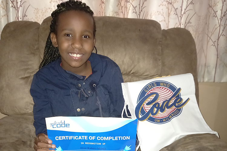 Photo of Elsie Maingi at her home in Nairobi, Kenya. Elsie shows off the certificate and tote bag she received from the Girls Who Code program at UWM. (Photo courtesy of Lilian Wangechi)