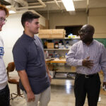 Photo of Dr. John Obielodan explaining the workings of a newly acquired selective laser sintering machine to some of his students in the lab. The machine was purchased through a Dairy Innovation Hub Supplies and Equipment grant.