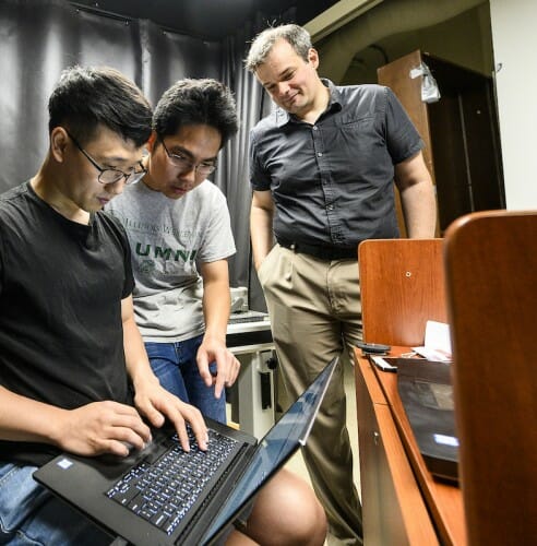 Photo of graduate students Ji Hyun Nam (left) and Toan Le working with assistant professor and principal investigator Andreas Velten in the Computational Optics lab. PHOTO: BRYCE RICHTER