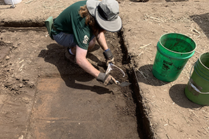 Photo of Field School student Arik Scapellato exposing a large circular feature stain in the excavation unit he is working in. (Photo courtesy of Seth Schneider)