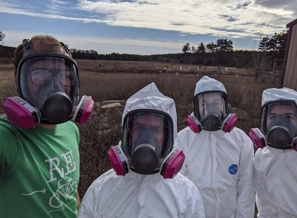 Photo of UW-Stevens Point researchers Alex Thomas, Professor Rob Michitsch, Amber Smith, and Susanne Baker preparing to work on research on the effects of composting on CWD-infected deer. Compost bins pictured in the background.