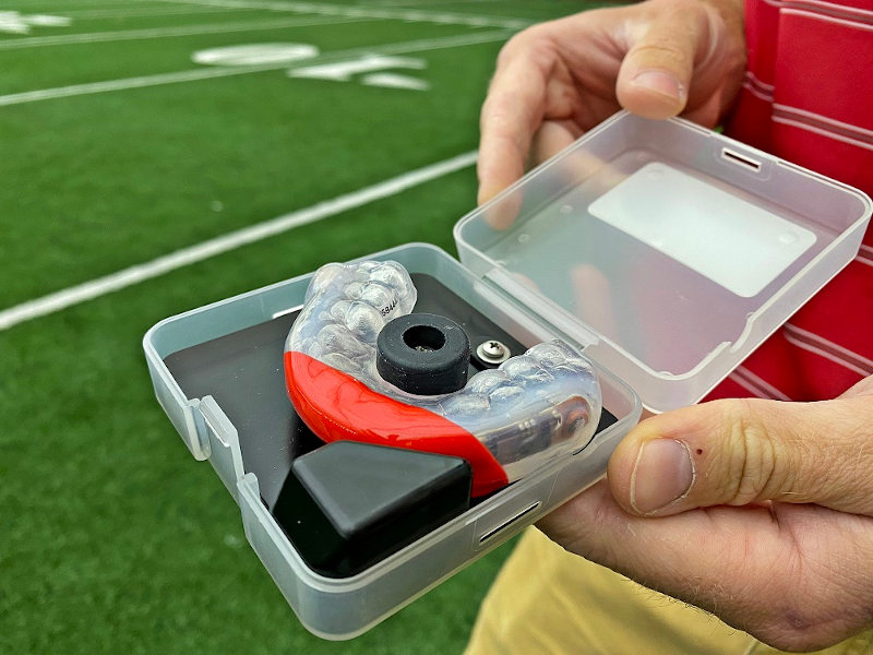 Photo of Daniel Cobian holding a specialized mouthguard that will be used by football players involved in the study. The sensors in the mouthguard will collect data on head impacts.