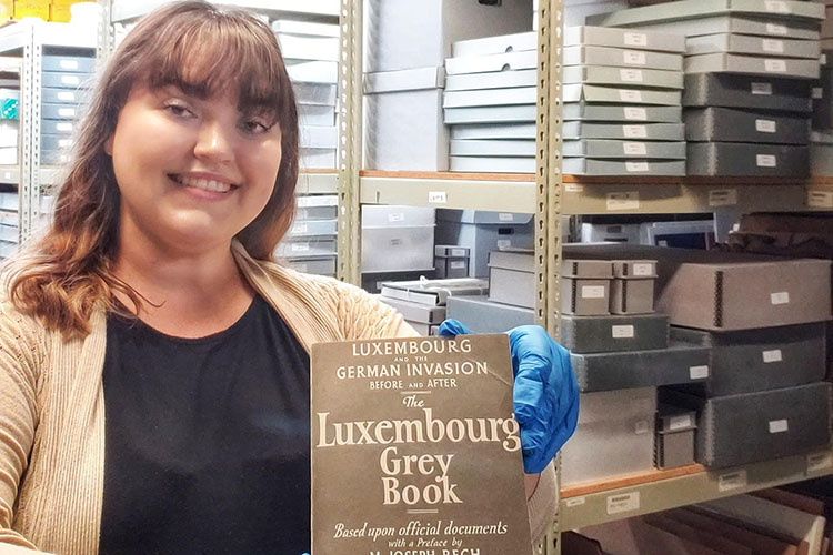 Photo of UWM history alumna Serena Stuettgen holding up an artifact from the archives at the Luxembourg American Cultural Society museum, where she is a curator. (Photo courtesy of Serena Stuettgen)