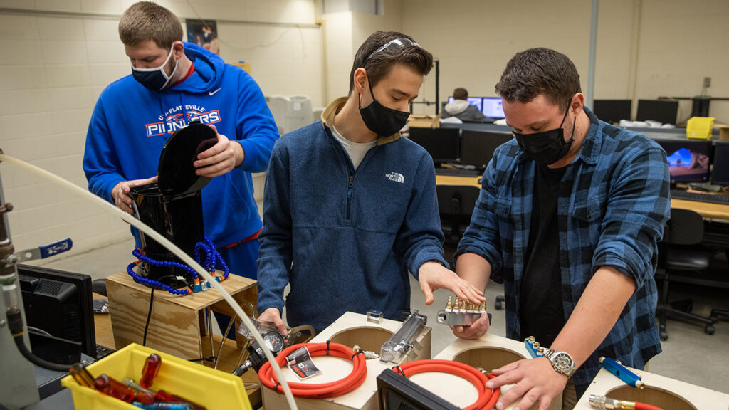 Photo of the Spectrum appliance cooling team assembling final prototypes of their life cycle testing coffee pot cooling solution. Pictured left to right are Daniel Redington, Michael Zelinsky and Curtis Marschall.