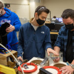 Photo of the Spectrum appliance cooling team assembling final prototypes of their life cycle testing coffee pot cooling solution. Pictured left to right are Daniel Redington, Michael Zelinsky and Curtis Marschall.